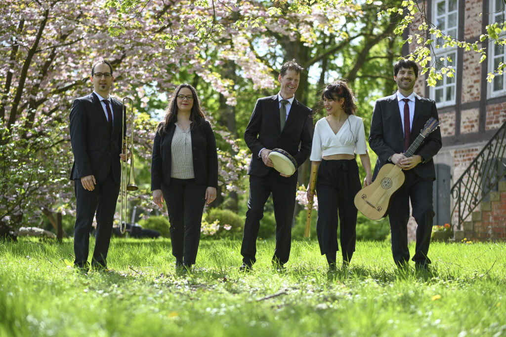 Die fünf Musiker und Musikerinnen von Concierto Iberico stehen in einem blühenden Garten.